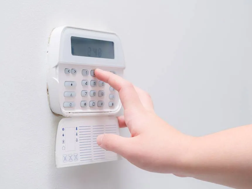 A hand entering a code on an alarm system keypad